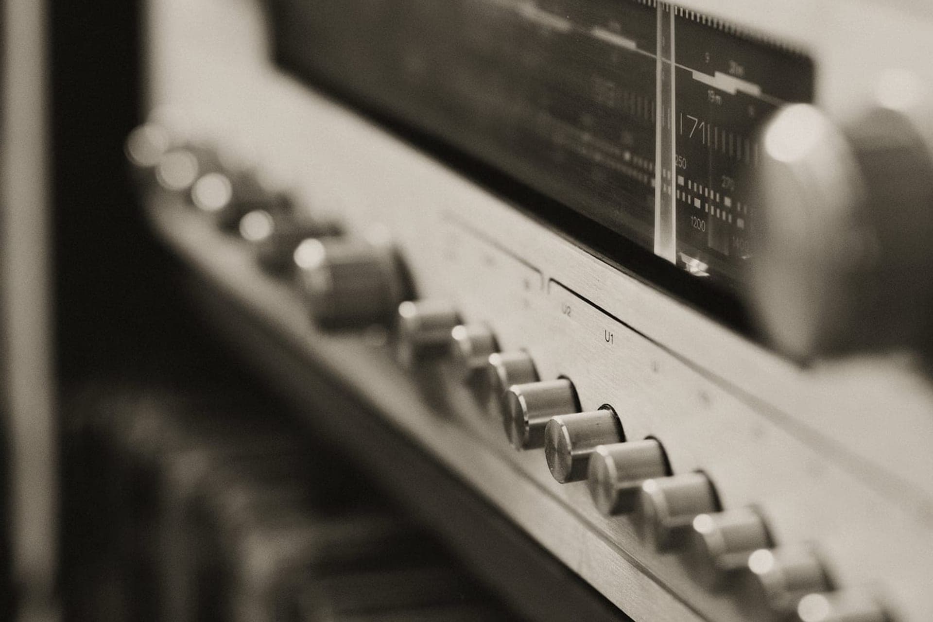 The control row and tuning dial of a vintage receiver in warm low-key light