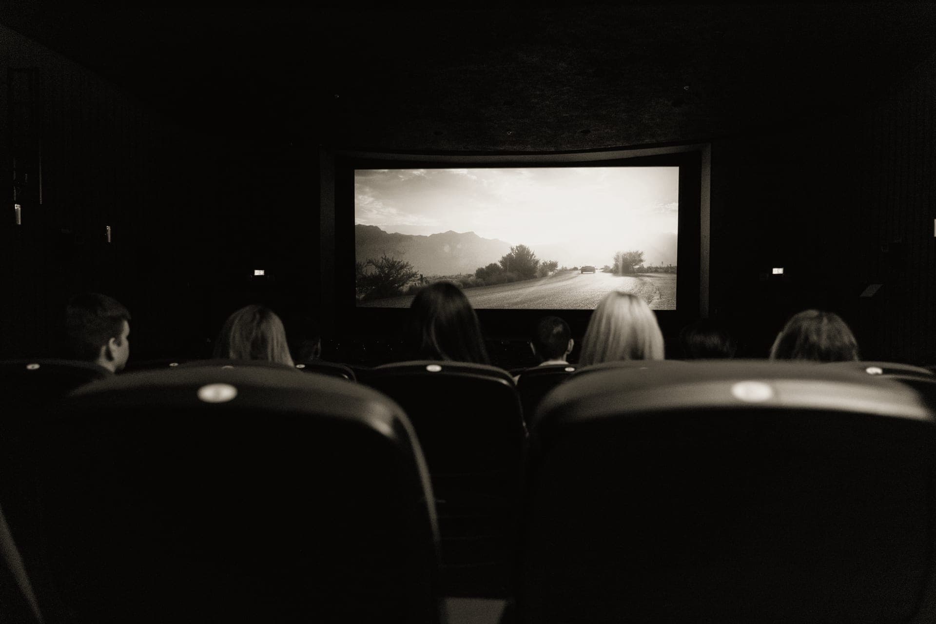 A dark home theater room with an AV receiver display glowing amber